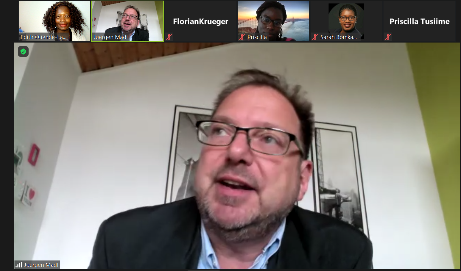 A man with glasses is talking to a group of people on a video call