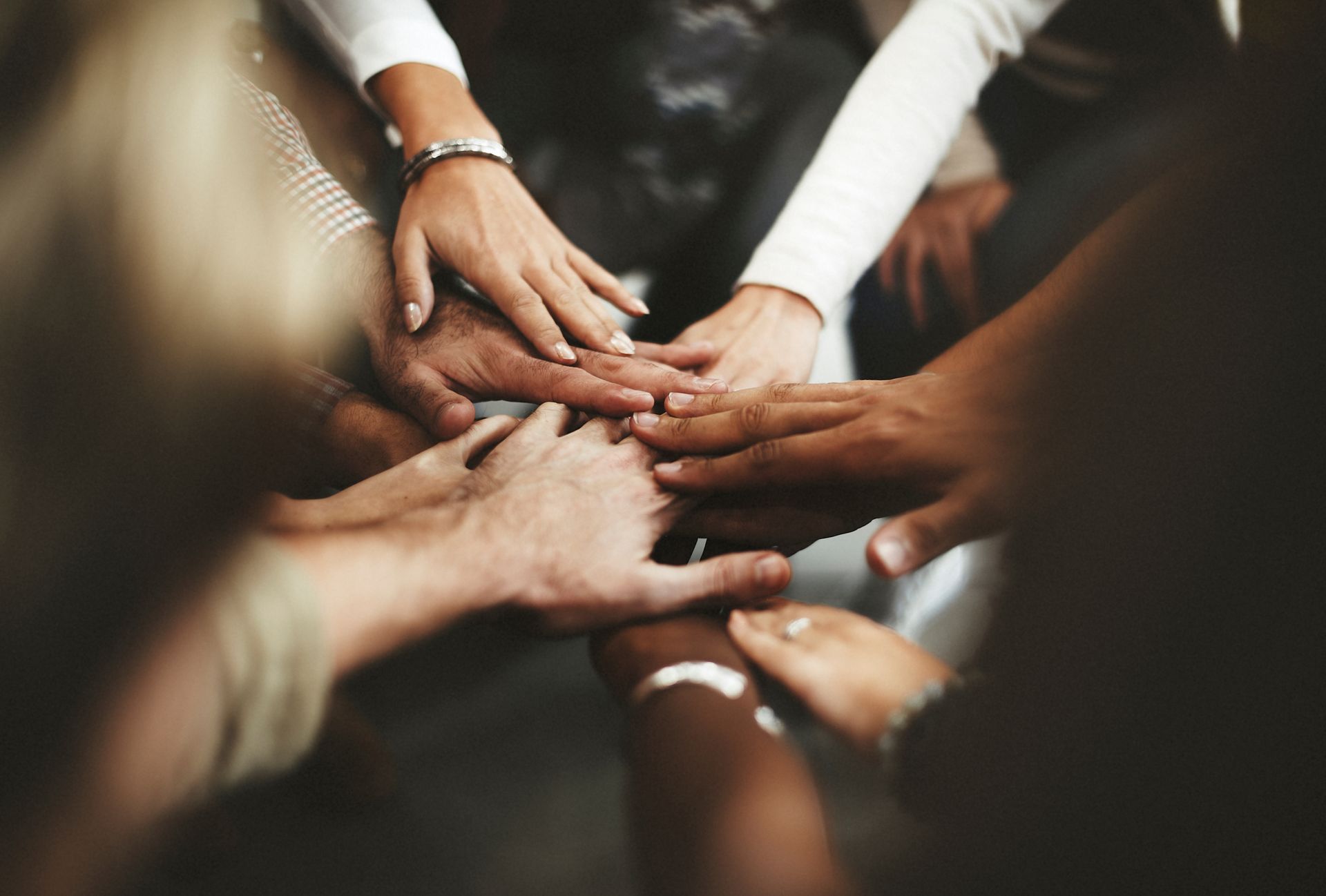 A group of people are putting their hands together in a circle.