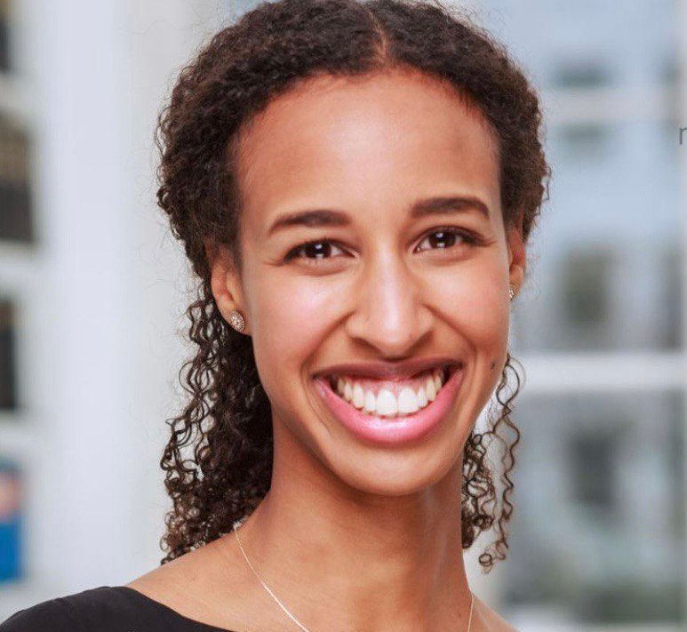 A woman with curly hair is smiling for the camera
