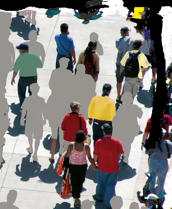 A large group of people are walking down a sidewalk