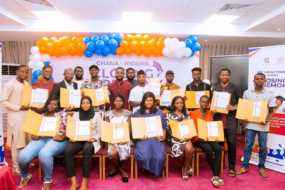 Group holding certificates on a stage with orange, blue, and white balloons, at a Ghana-Nigeria event