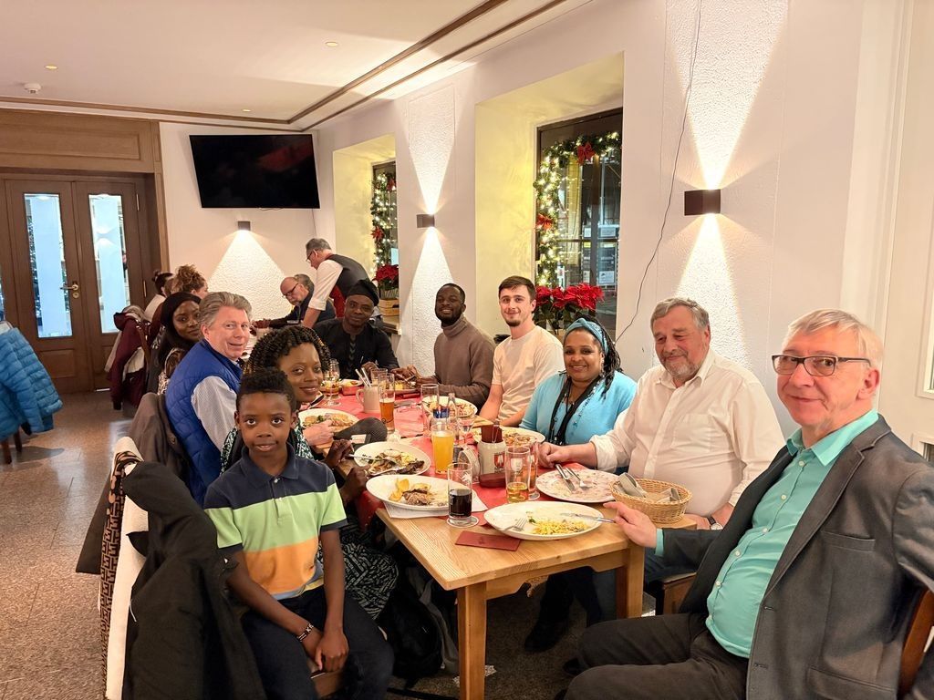 People seated around a table, enjoying a meal in a warmly lit dining area.