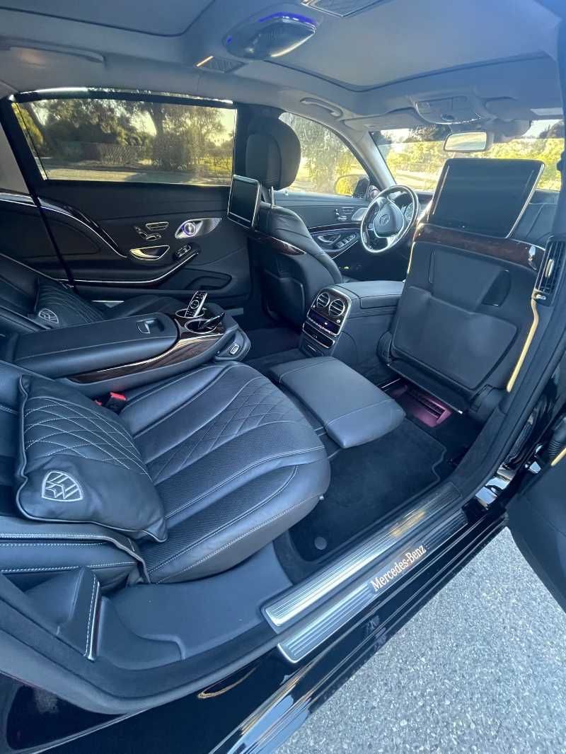 The interior of a black mercedes benz maybach s class with the door open.