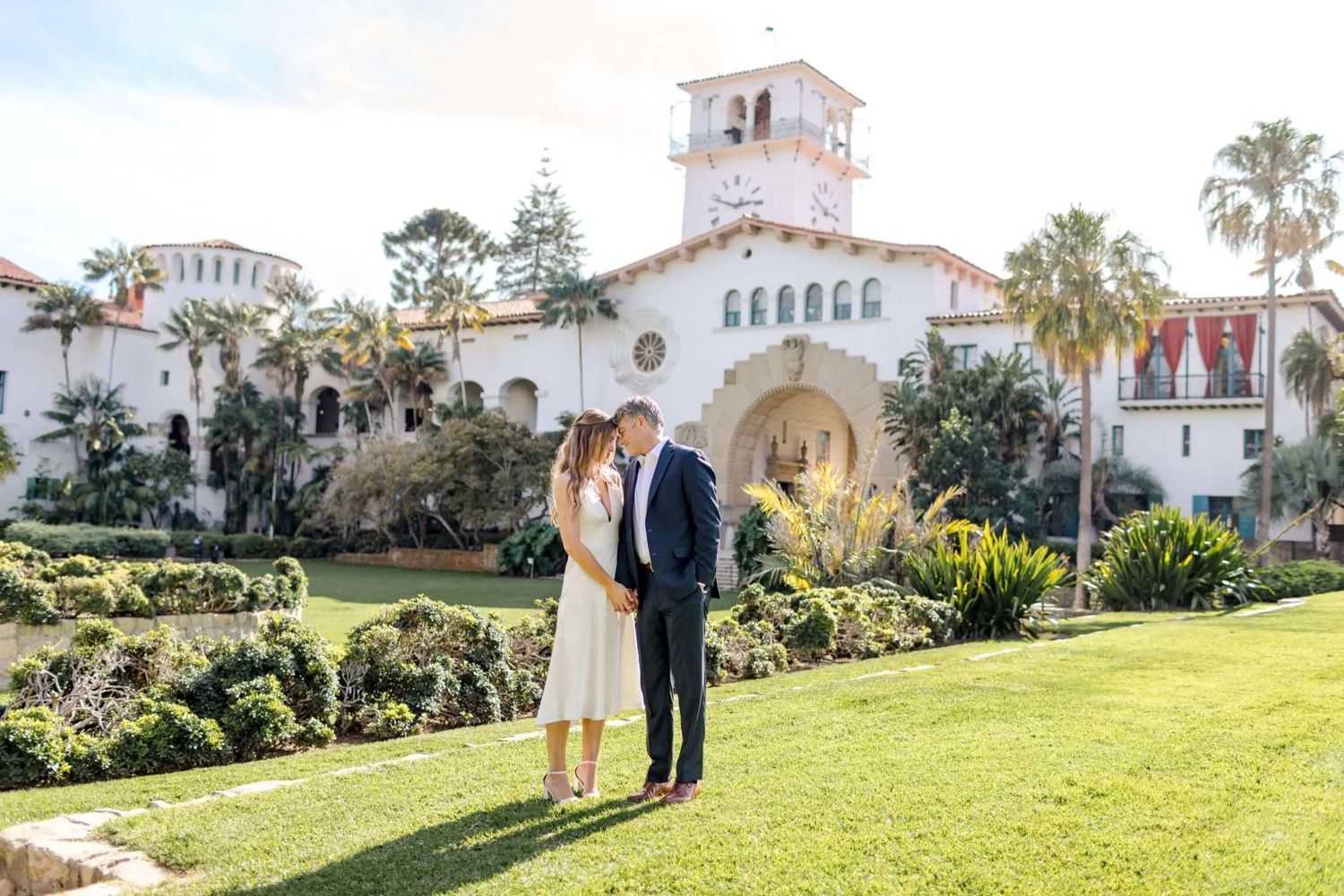 A man and a woman are standing in front of a large white building.