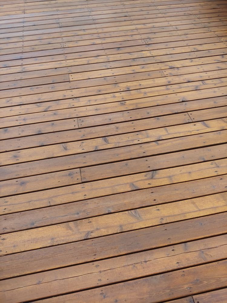 Weathered wooden deck planks with a few scattered leaves and dark spots