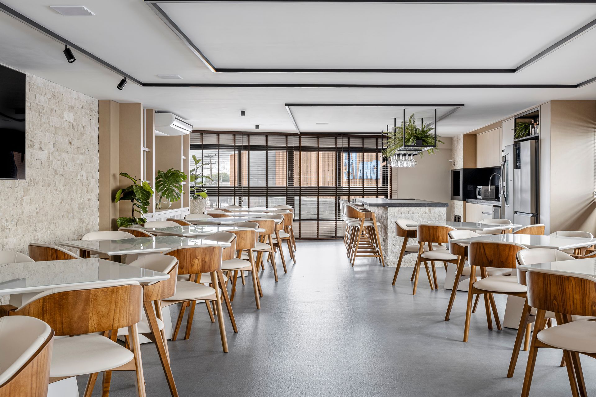 Sala de jantar moderna com cadeiras de madeira clara, mesas brancas e piso cinza.