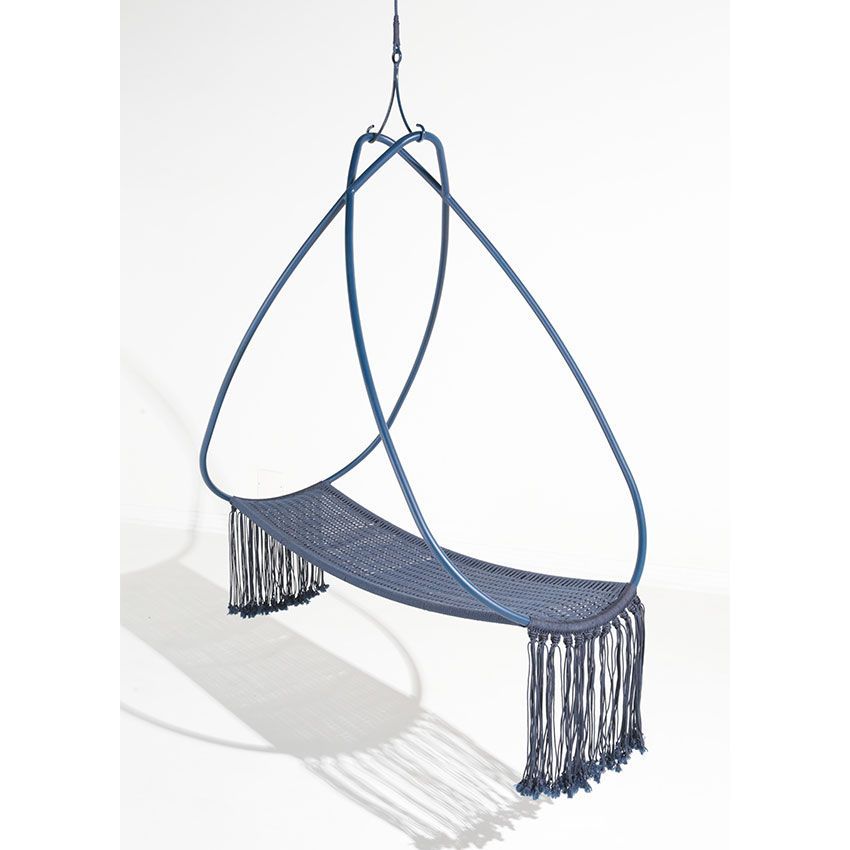 Cadeira suspensa azul com estrutura em forma de lágrima e assento com franjas, suspensa sobre uma superfície branca.