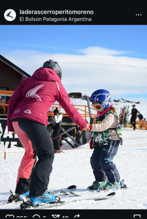 Una mujer está ayudando a un niño a esquiar por una pendiente cubierta de nieve.