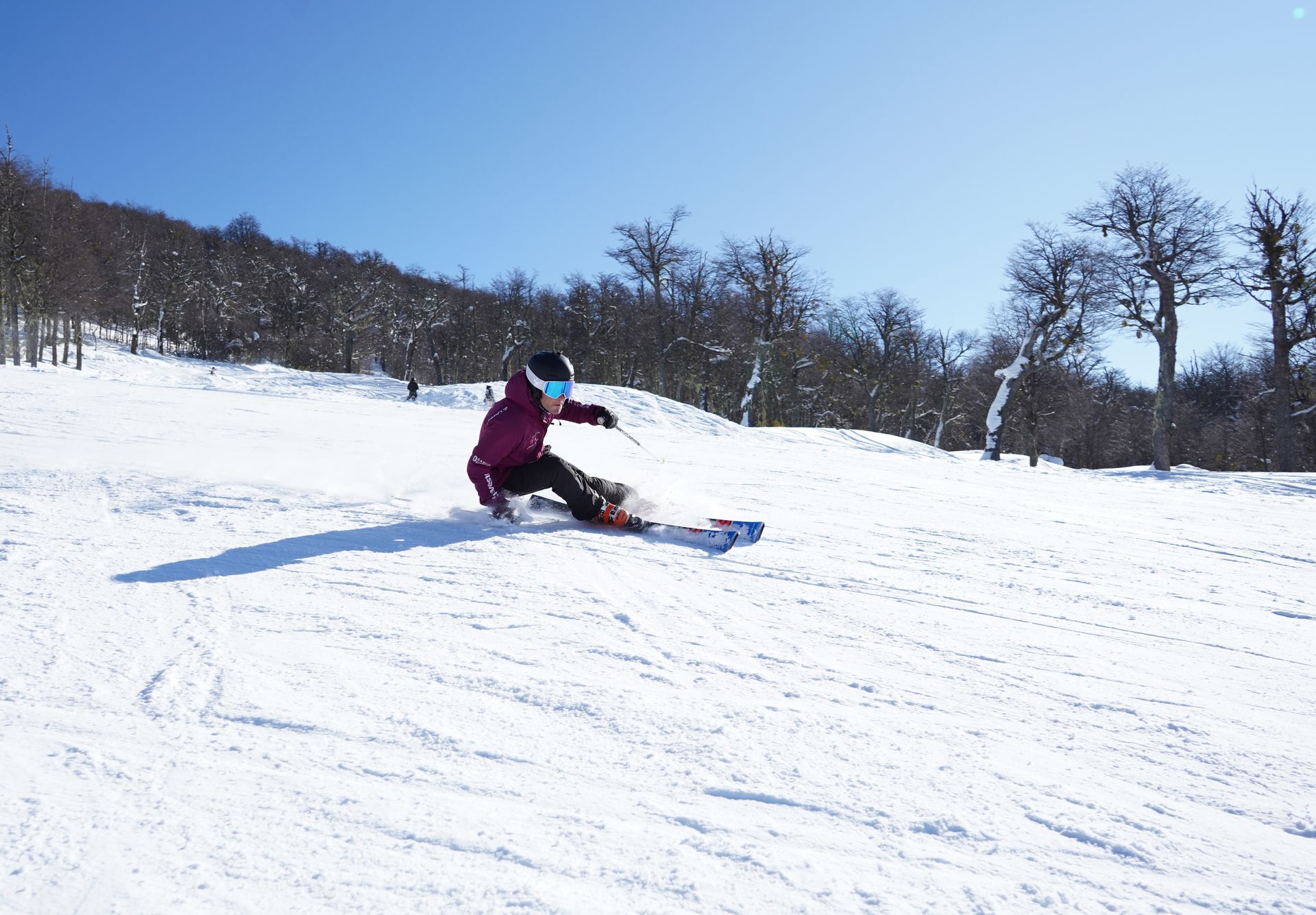 Un snowboarder desciende por una pendiente cubierta de nieve en un día soleado.