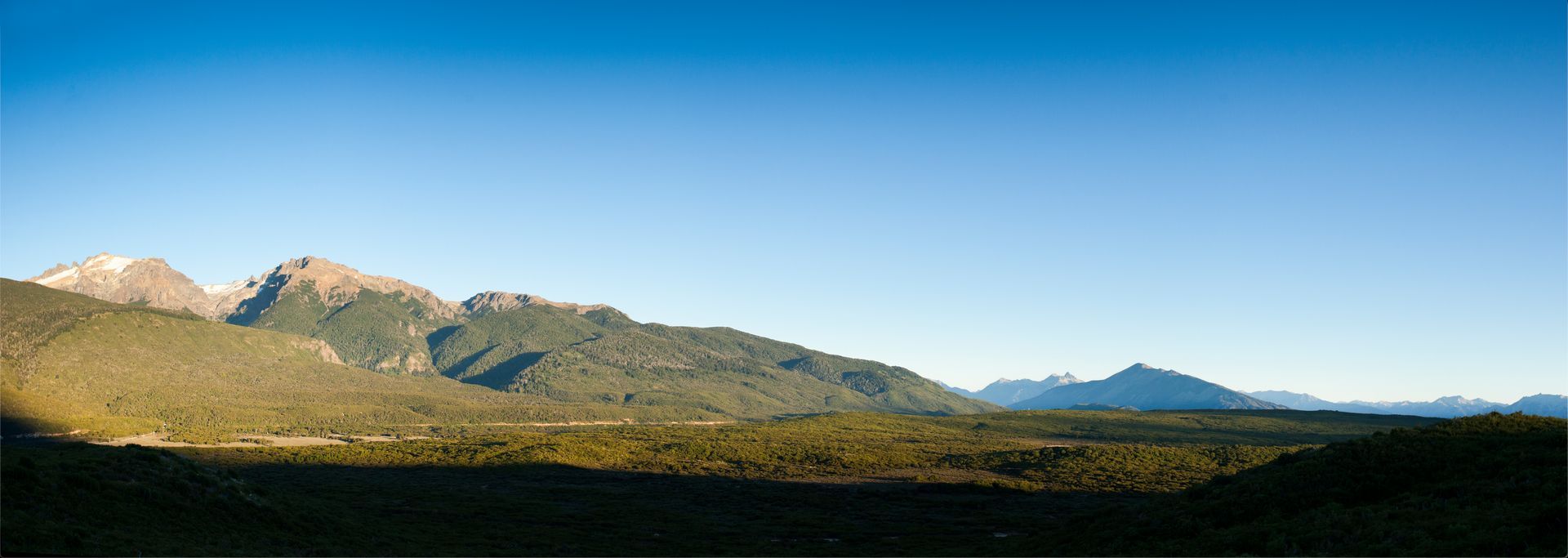 Montañas con algo de nieve en la cima y un cielo azul profundo en el fondo.