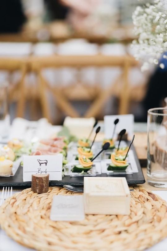 Table setting with appetizers on a rustic placemat; a cheese board and flower arrangement are visible.