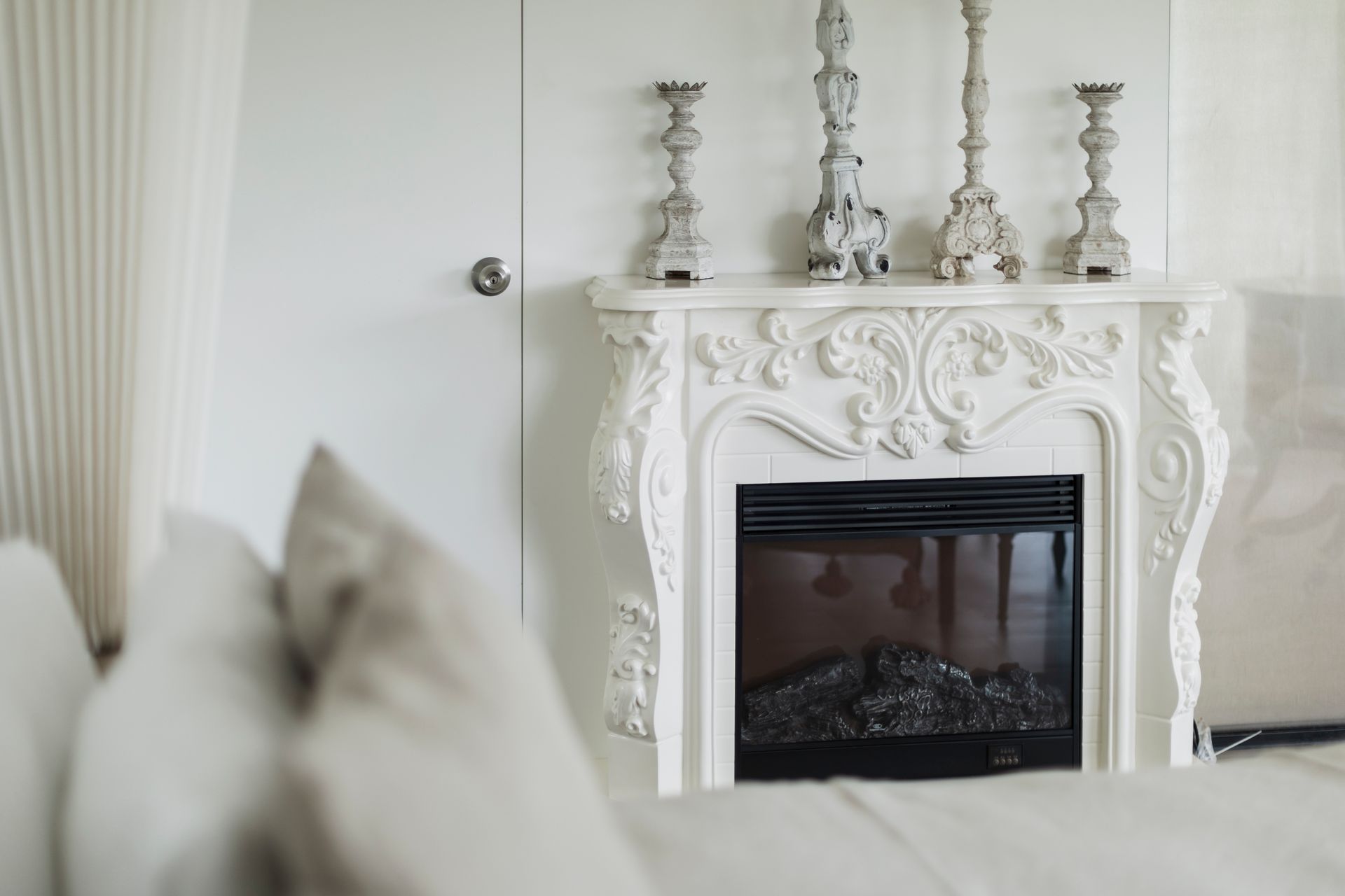 White fireplace with ornate carvings and candle holders on the mantel.