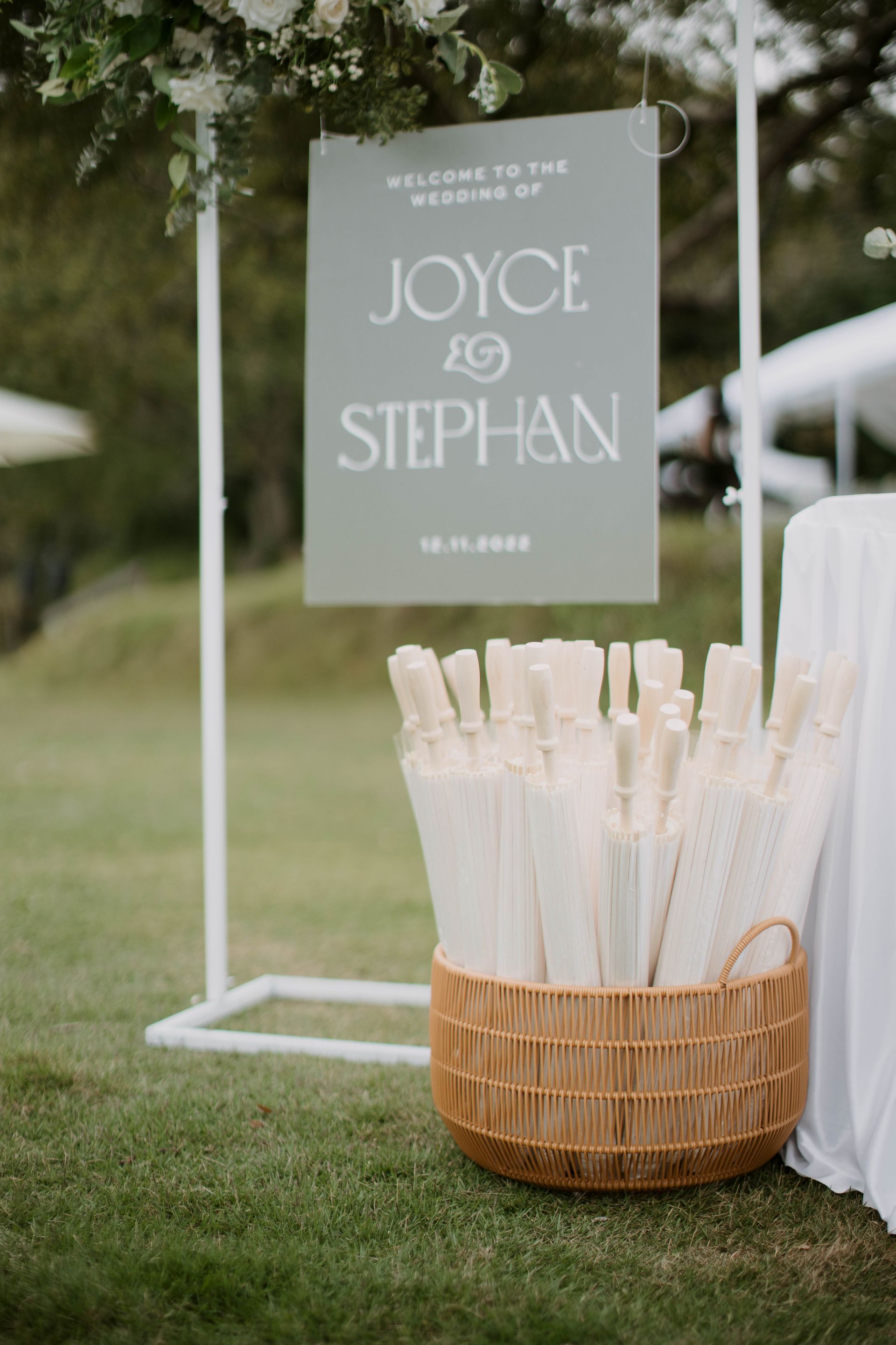 Welcome sign at Joyce & Stephan's wedding, with basket of parasols.