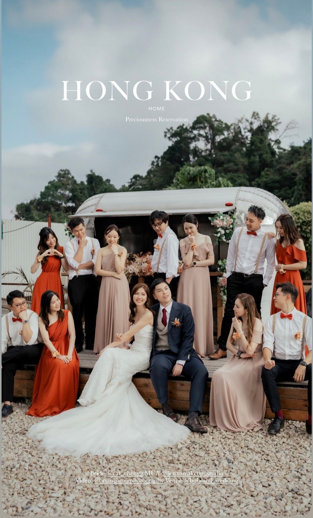 Wedding party in Hong Kong: bride and groom seated with group in front of an outdoor trailer, bridesmaids in red and blush.