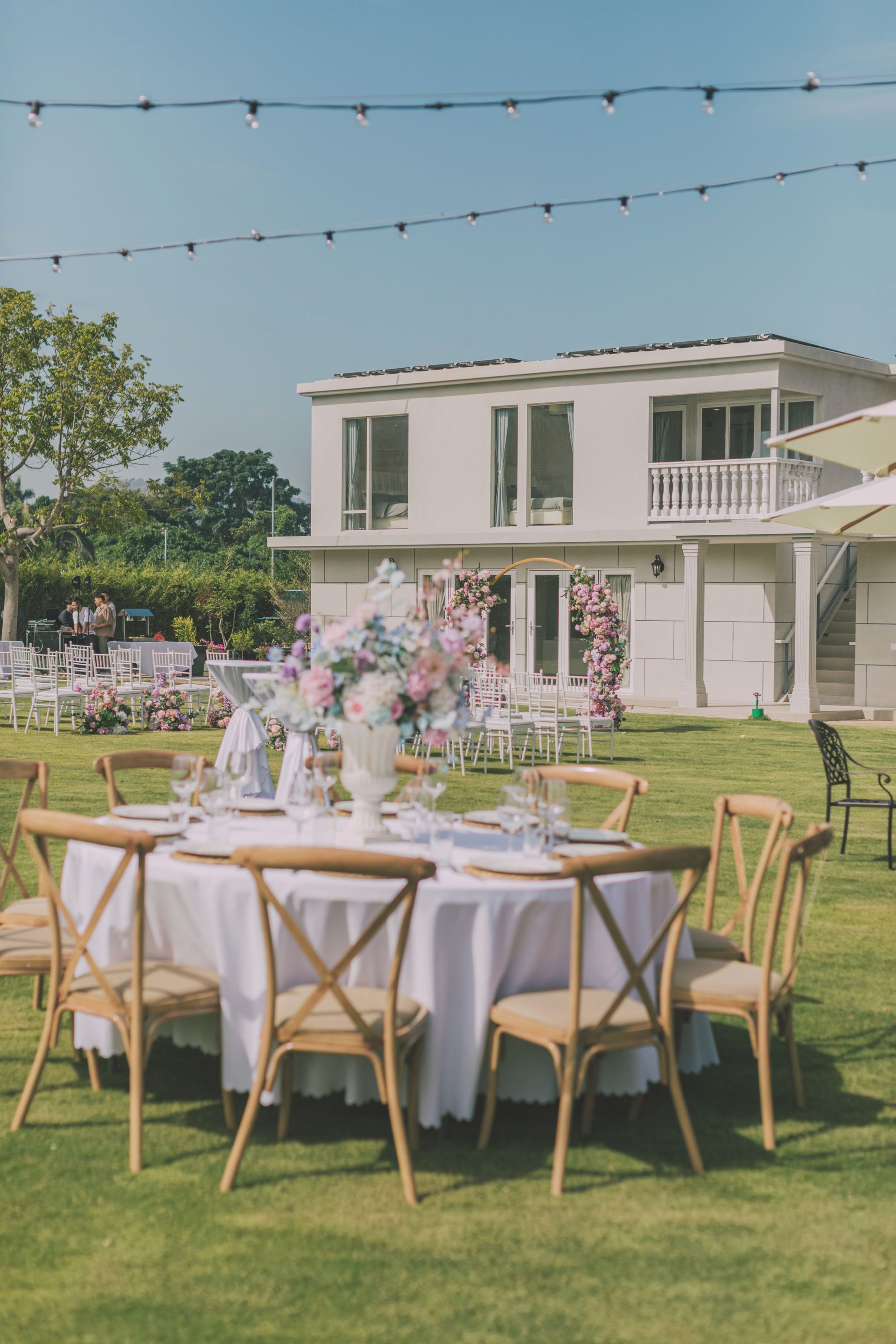 Outdoor café seating on a grassy lawn with white umbrellas and black tables and chairs