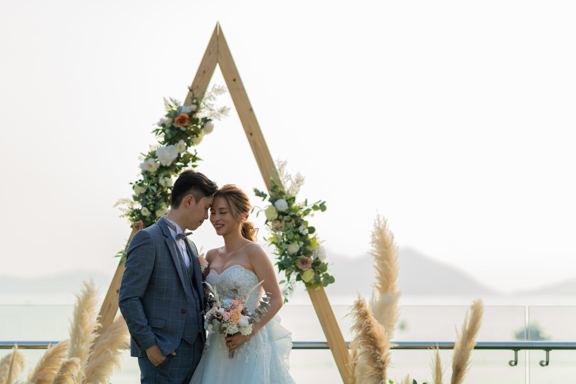 Couple at a wedding ceremony, embracing under a floral archway.