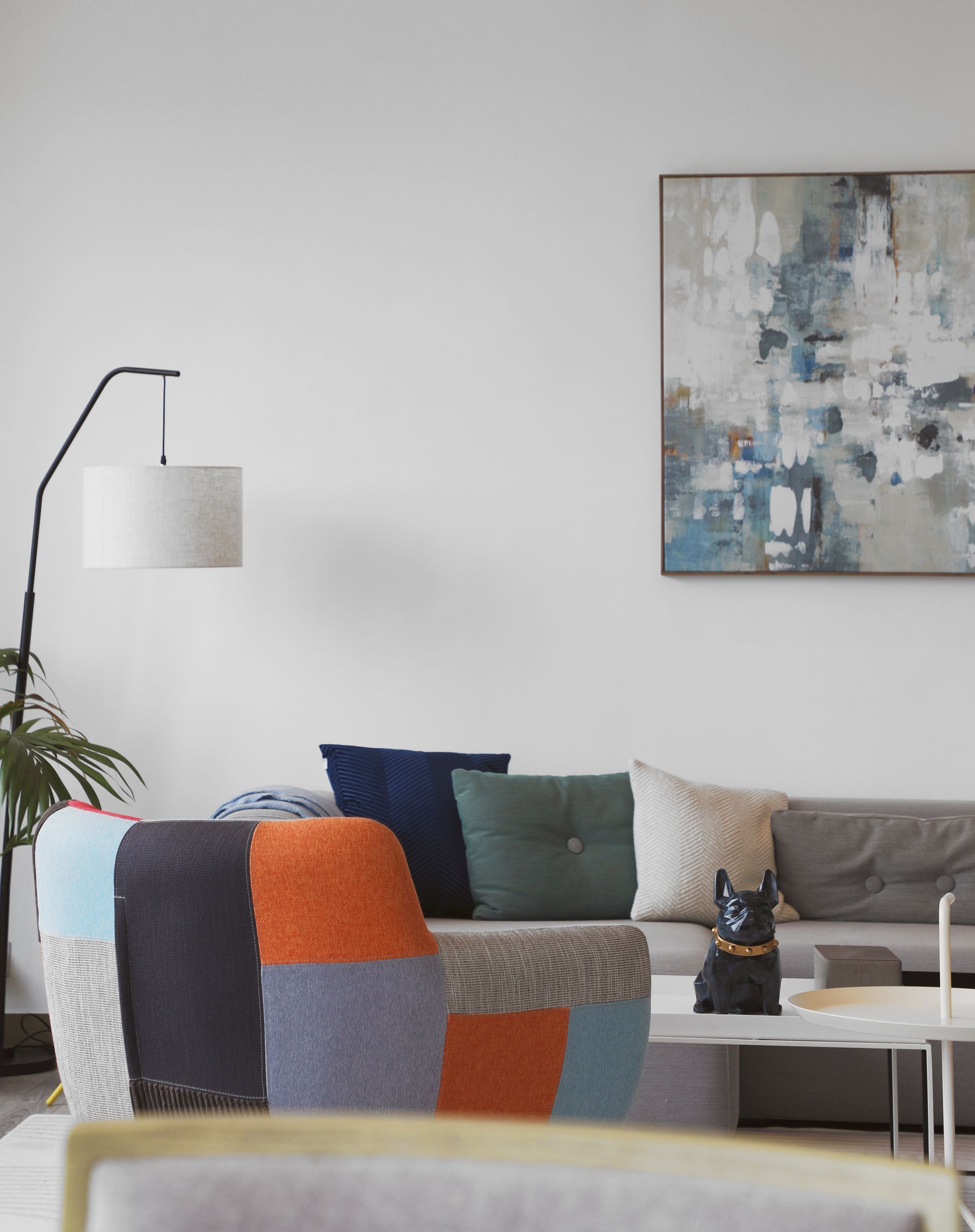 Living room with sofa and pillows, abstract art, floor lamp, and a small table.