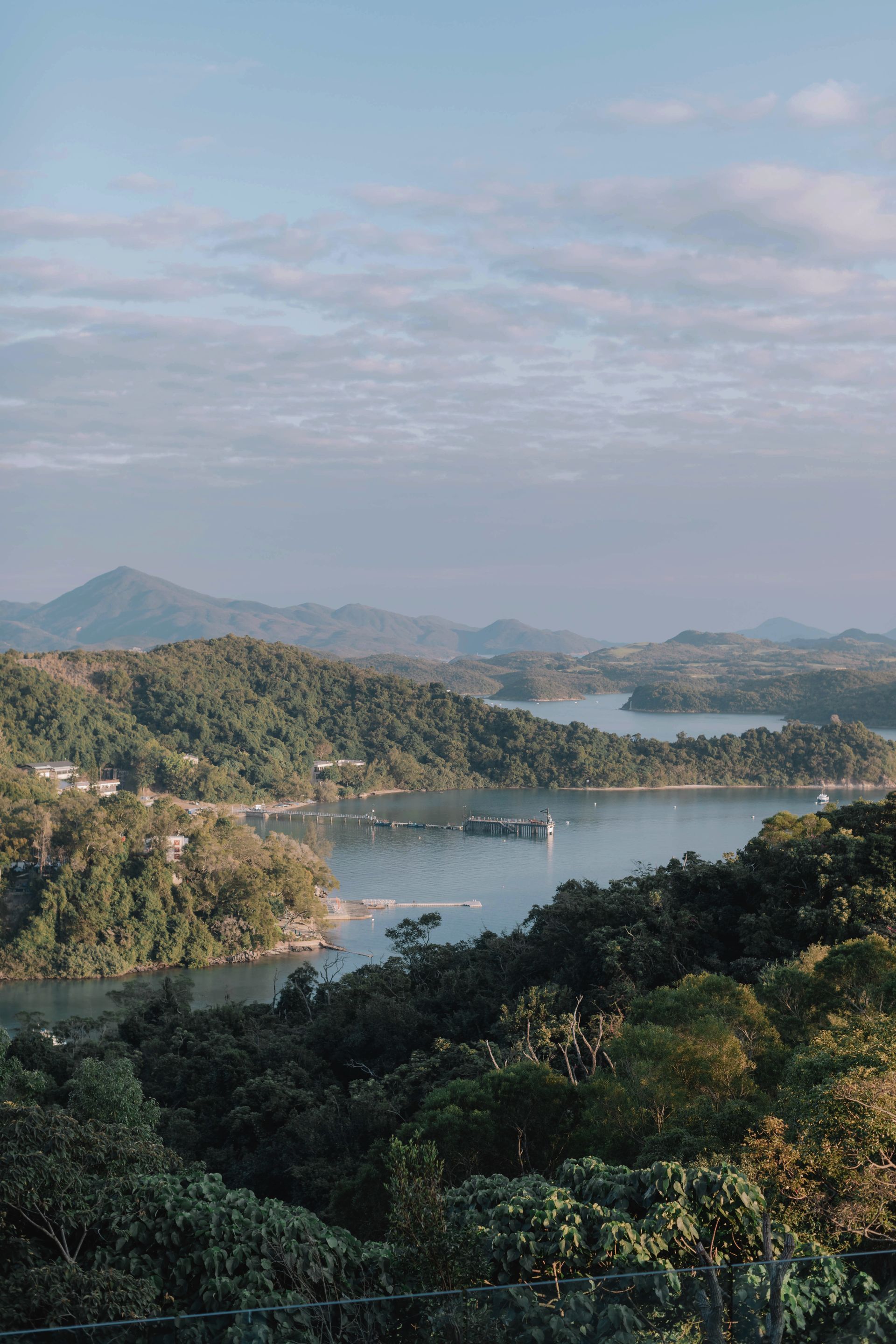 Overlooking a serene lake surrounded by lush green hills under a partly cloudy sky.