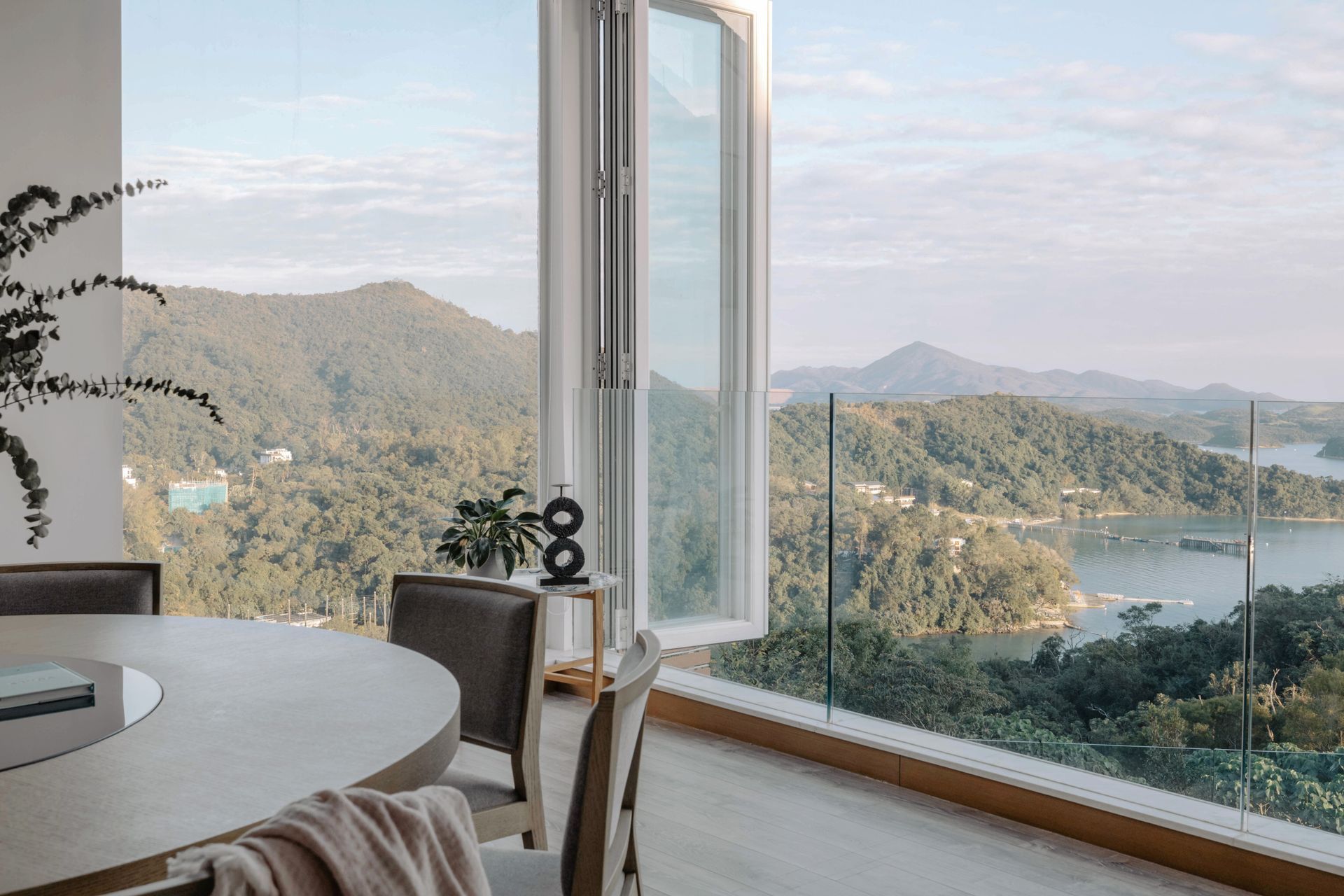 Dining room with open window overlooking lush green mountains and water.