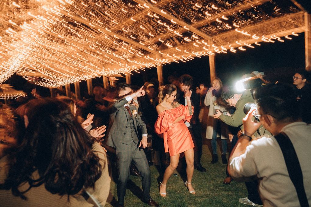 People dancing under string lights at an outdoor event.