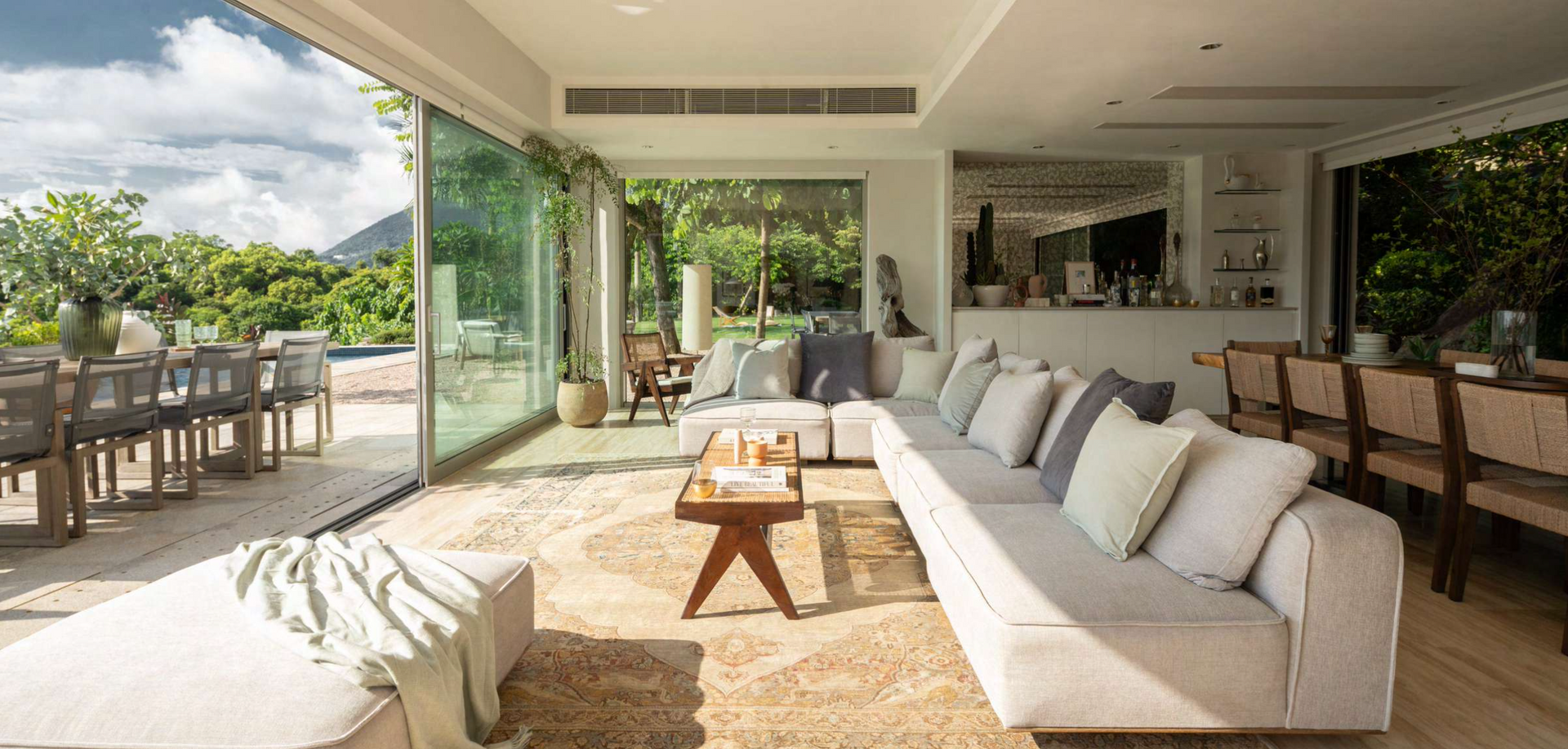 Open-plan living room with large sliding doors leading to a patio and garden area. Neutral colors and natural light.