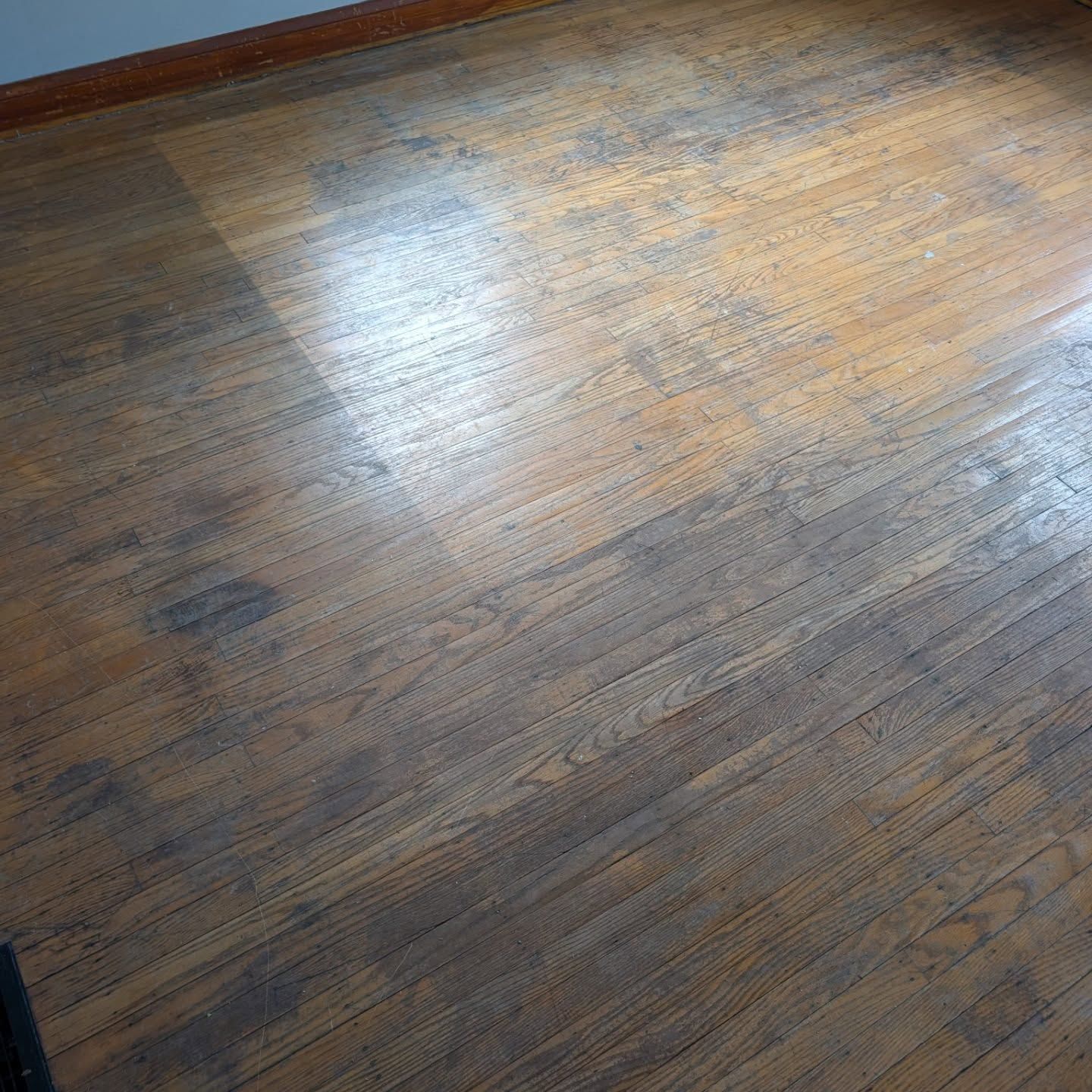Close-up of a worn wooden floor with sunlight reflecting on the surface
