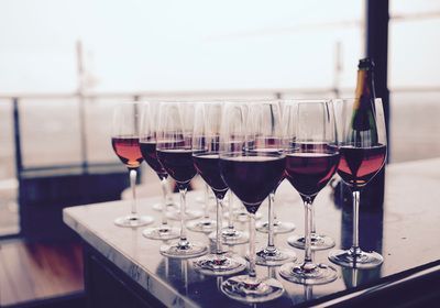 Wine glasses filled with red wine on a counter, bottle visible in the background.