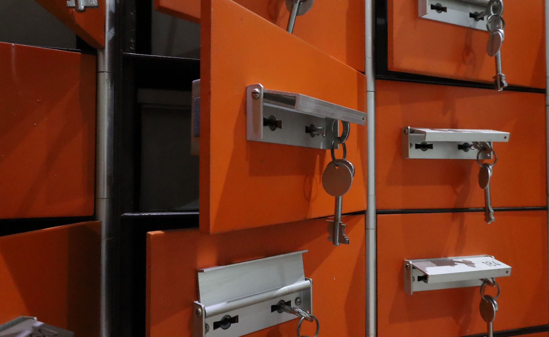 Casiers orange avec des poignées argentées, l’un des casiers ouvert laissant voir une clé dans la serrure