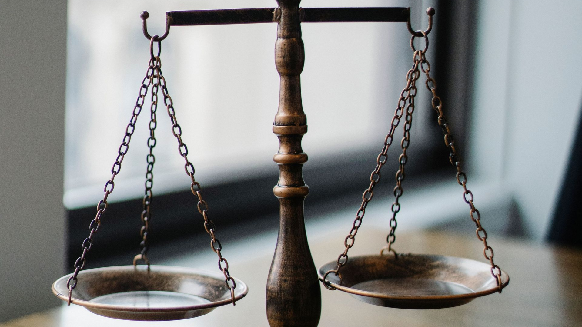 Une balance en bois à deux plateaux suspendus, posée sur une table, symbole de justice.
