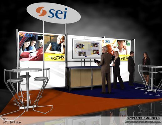 Trade show booth with SEI logo, people interacting. Orange, white, and blue design with display screens and tables.