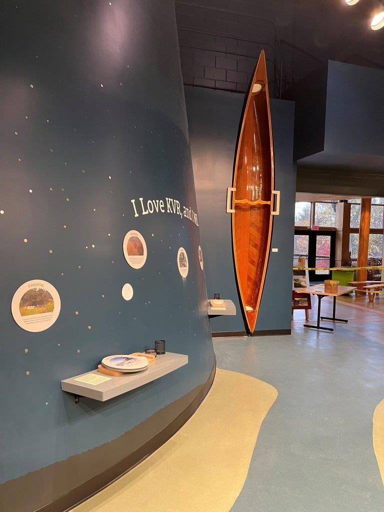Interior with a wooden canoe suspended on a blue wall with educational displays.