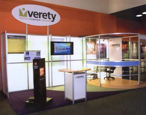 Verety booth at an event. Orange and white walls, a screen, and a logo are visible.