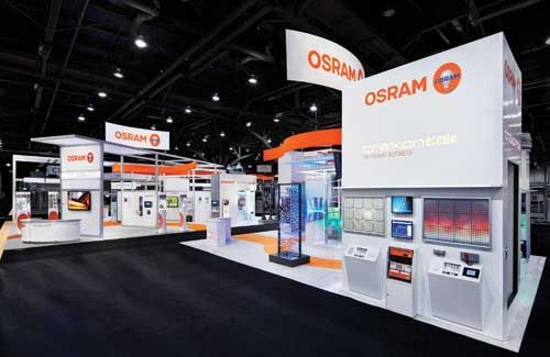 OSRAM trade show booth with orange and white displays and signage, showcasing lighting products. OSRAM trade show booth with orange and white displays and signage, showcasing lighting products.