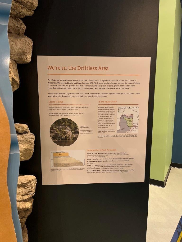Sign about the Baraboo area with text, diagram, and photo, mounted on black wall.