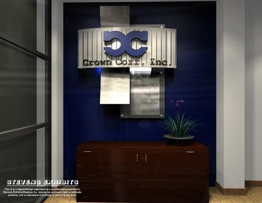 Crown Corp., Inc. logo on a blue wall above a brown cabinet, next to a door. A small plant sits atop the cabinet.