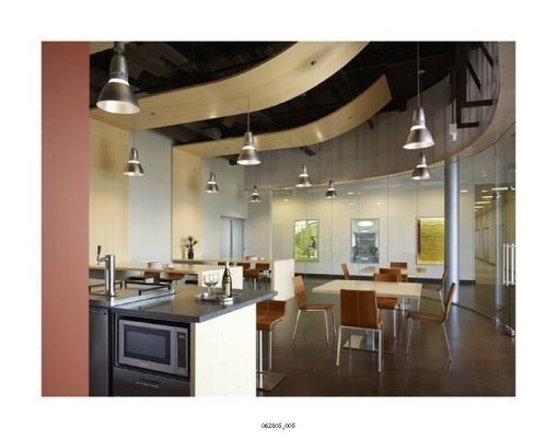 Modern kitchen and dining area with curved wooden ceiling accents, pendant lights, and glass walls.
