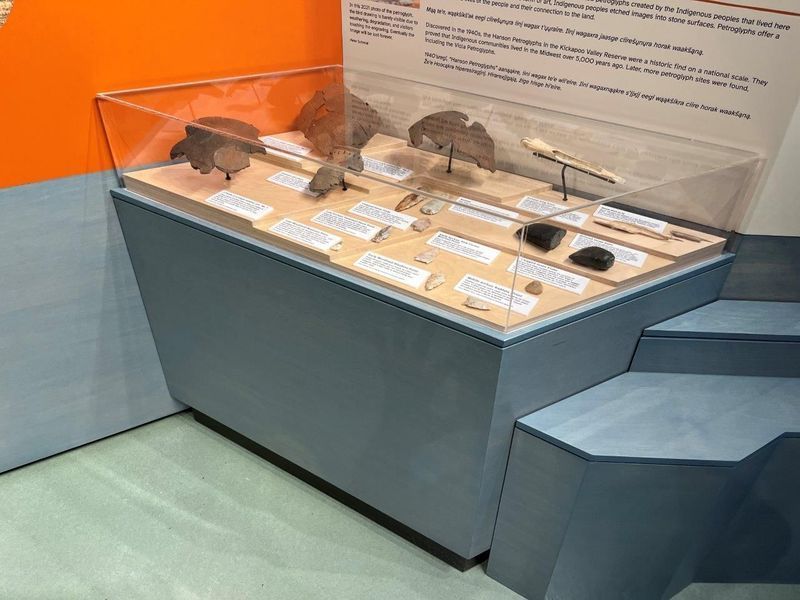 Museum display case with artifacts, informational text, and a gray, blue, and orange color scheme.