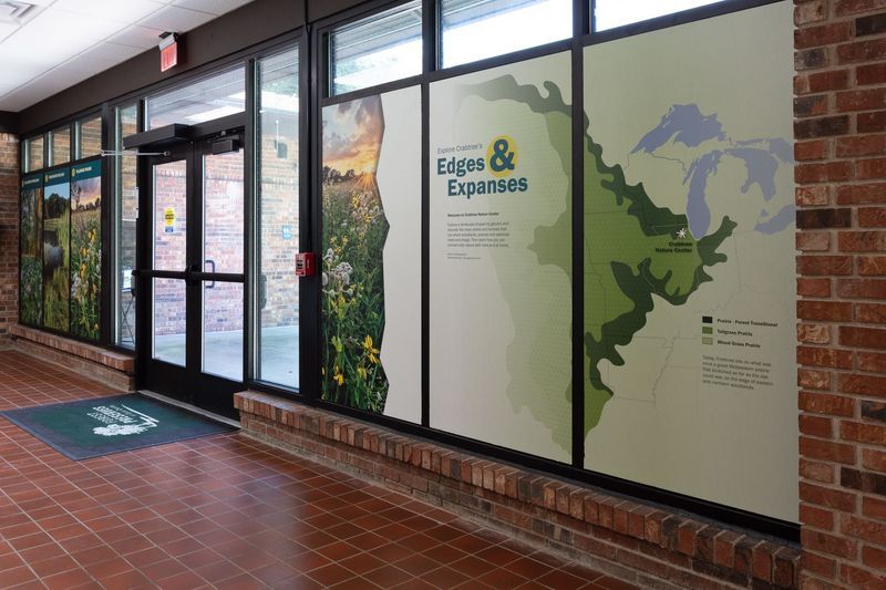 Hallway with glass windows displaying nature scenes and a map labeled 