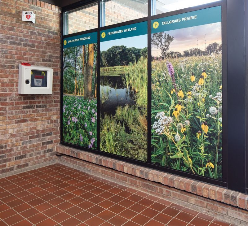 Exterior with brick wall, glass panels showing photos of landscapes, an AED mounted on the wall.