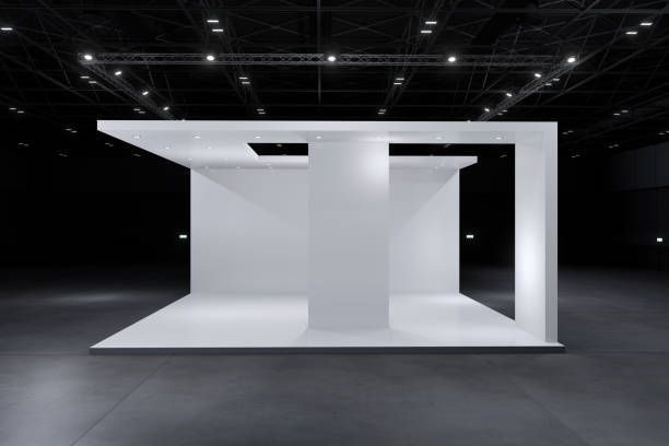 White trade show booth in a dark exhibition hall.