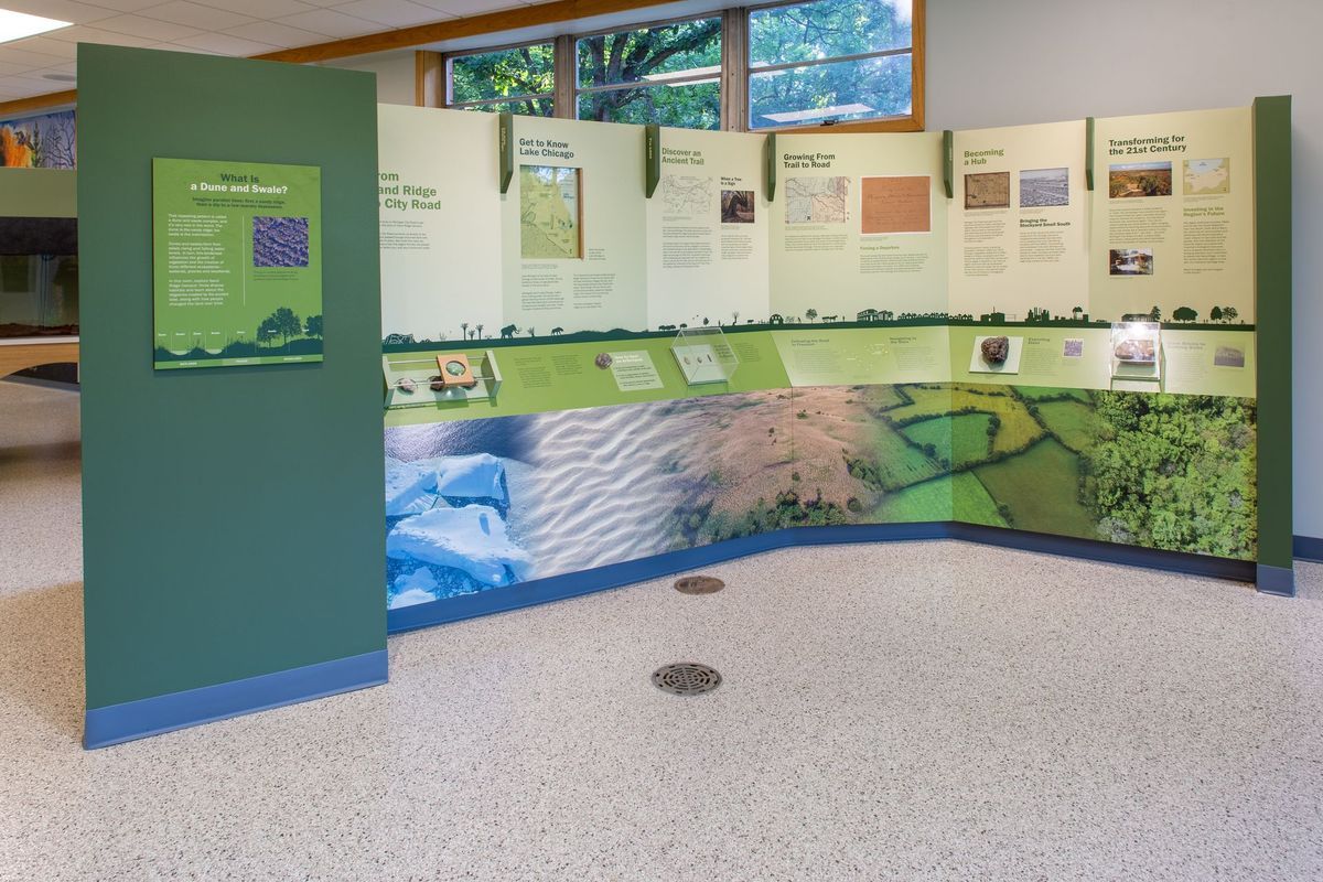 Museum exhibit with green panels, showcasing information with graphics and text.