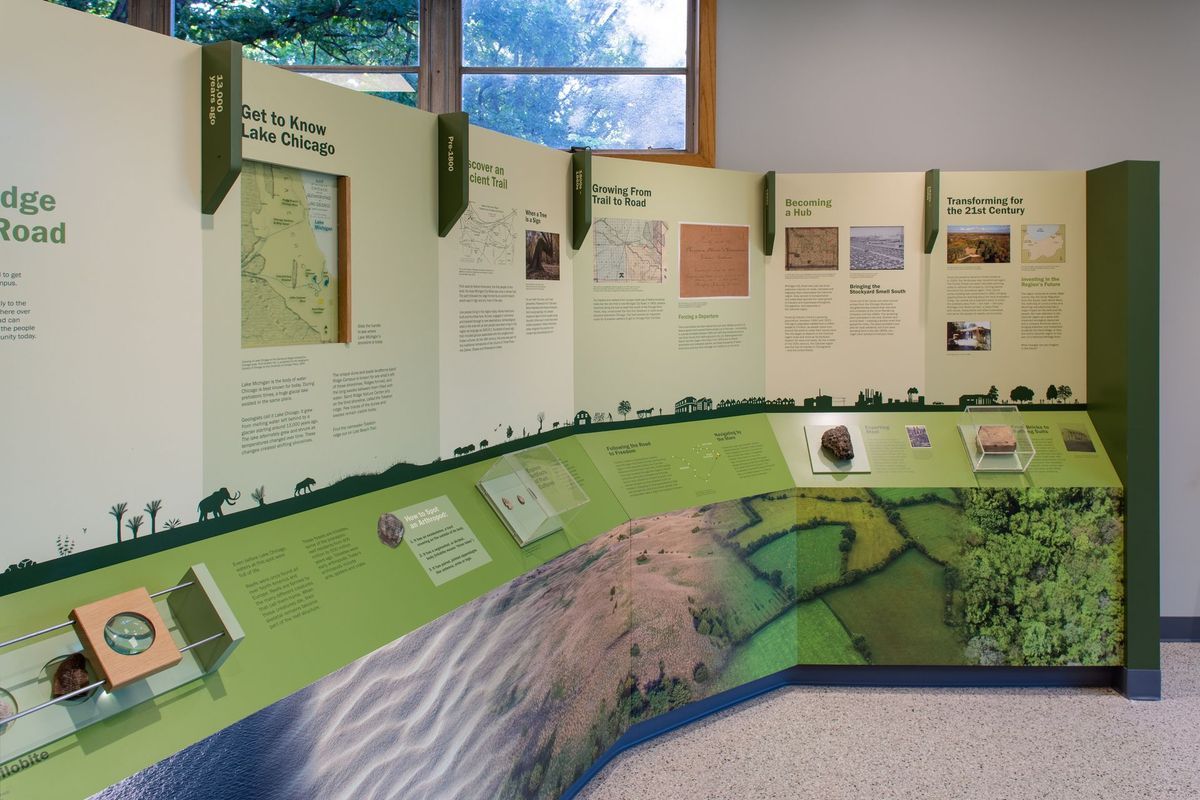 An exhibit featuring informational panels, maps, and artifacts, with a green and beige color scheme.