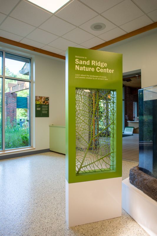 Sign in a nature center with green and white panels, and a decorative leaf design.