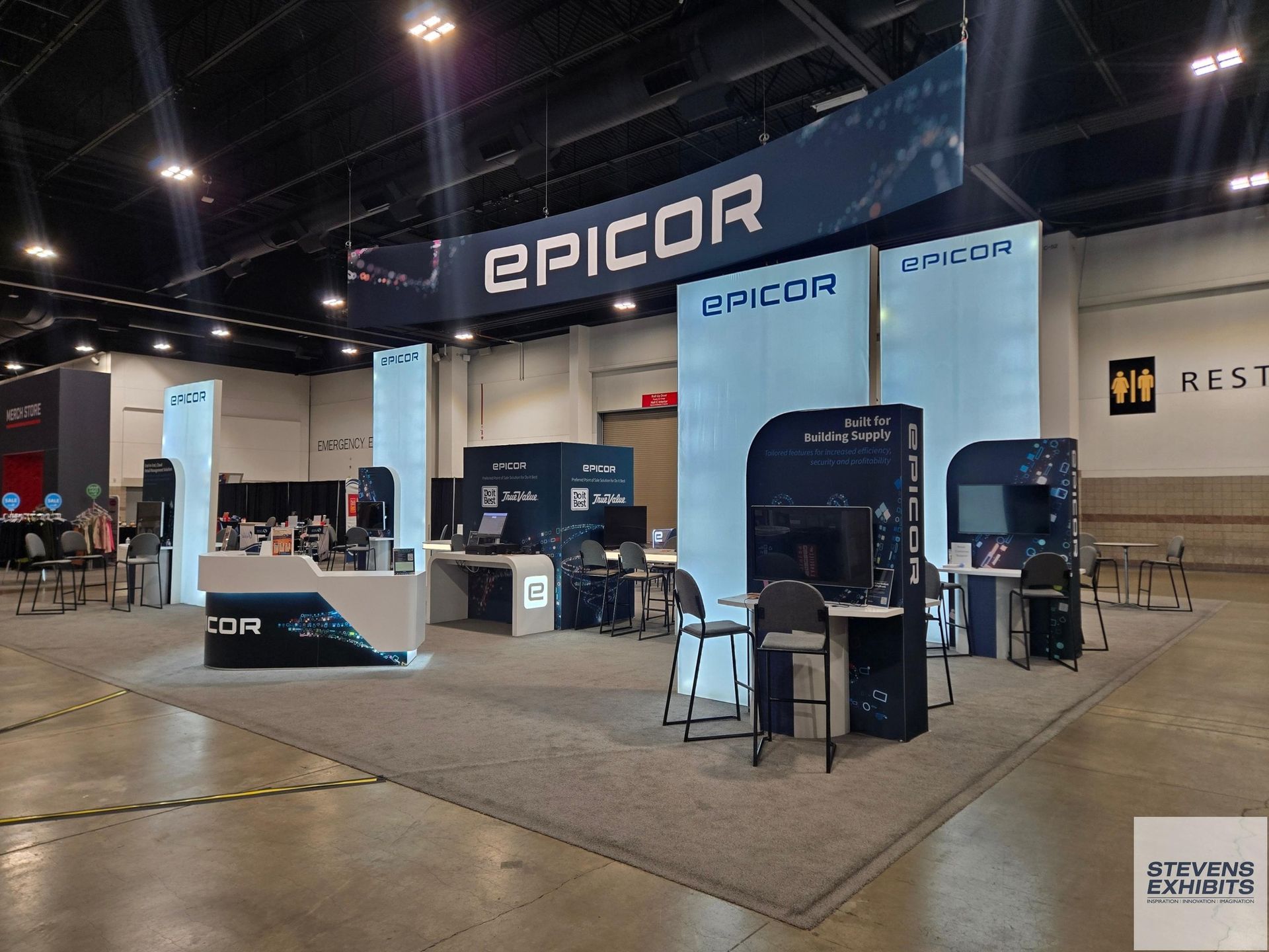 Modern trade show booth with wooden accents and digital displays. Features a bar and lighting.