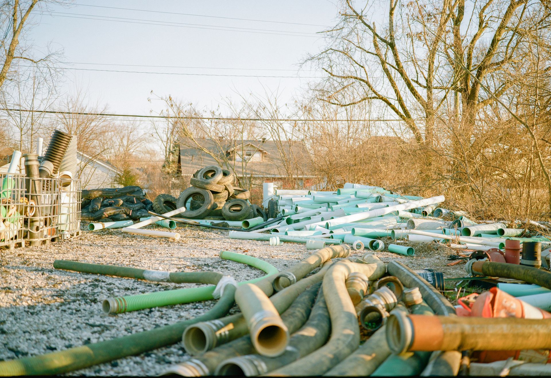 A pile of pipes is laying on the ground in a yard.