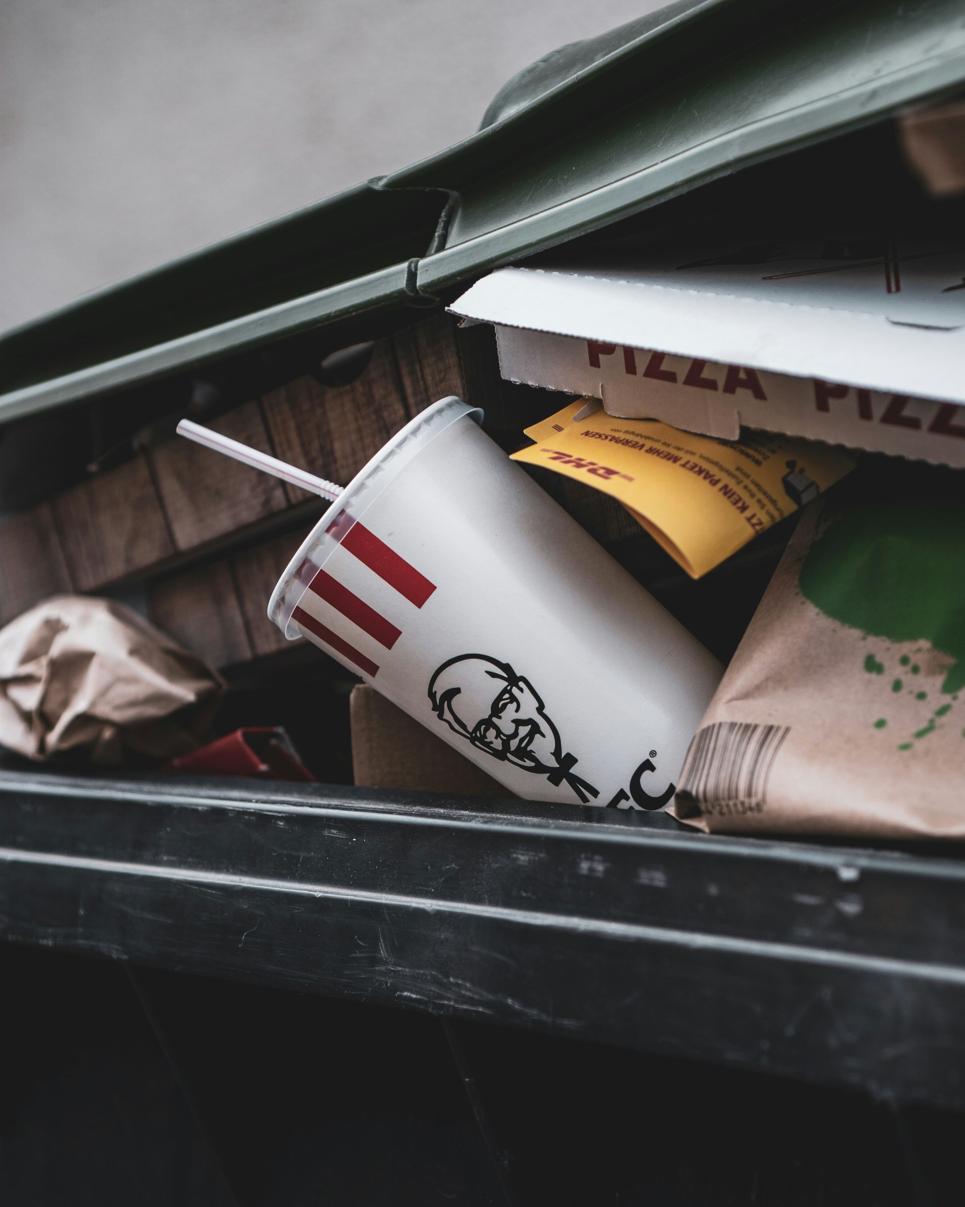 A trash can filled with food including a kfc cup