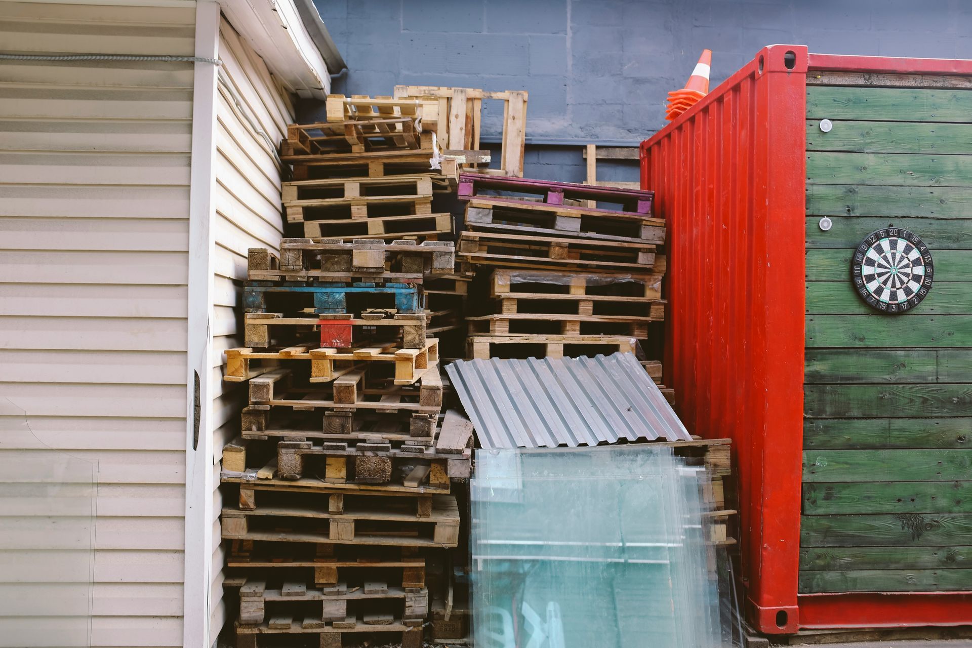 A stack of wooden pallets and a dart board in front of a building.