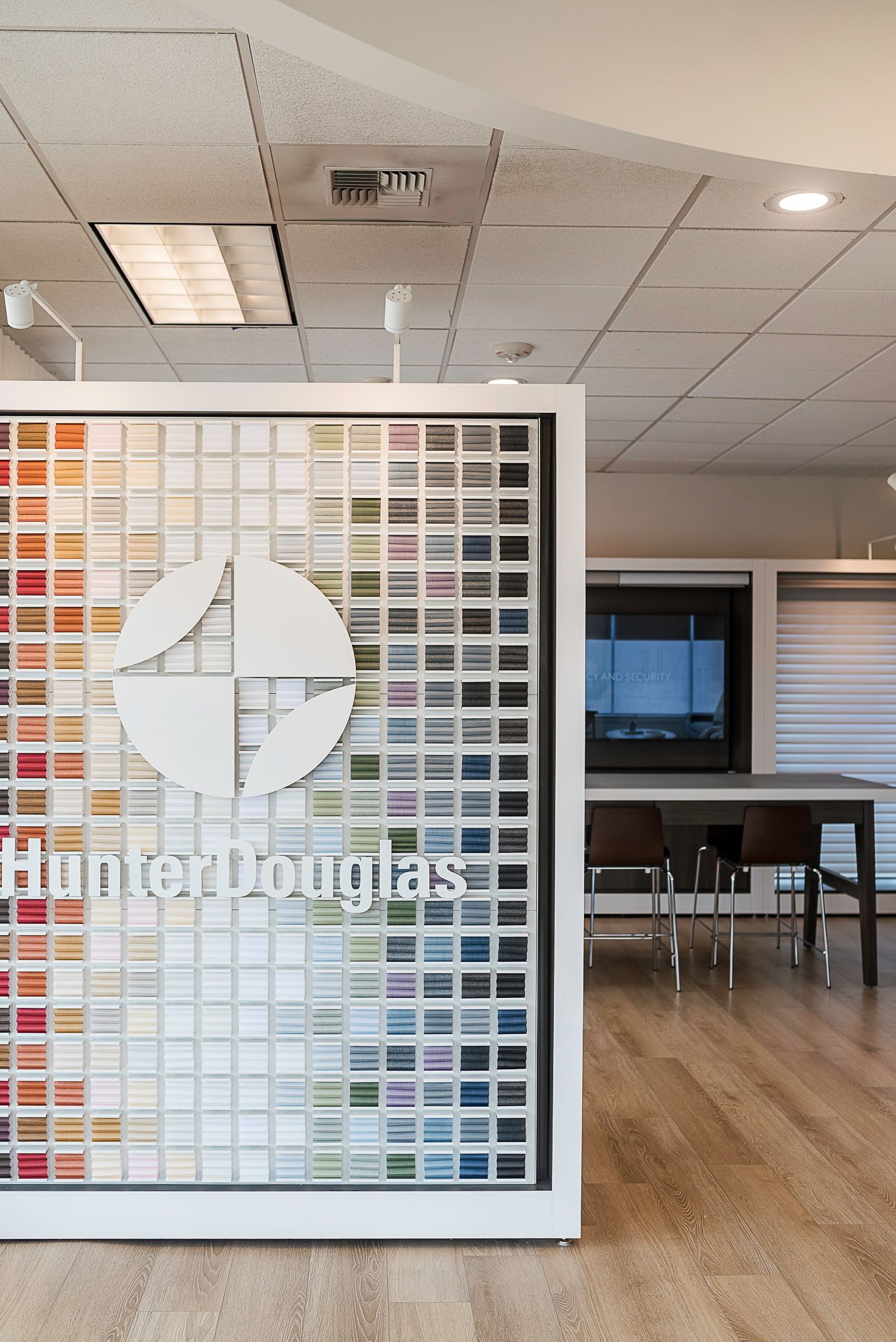 Color swatch display in a showroom with a meeting area and wood floor in the background