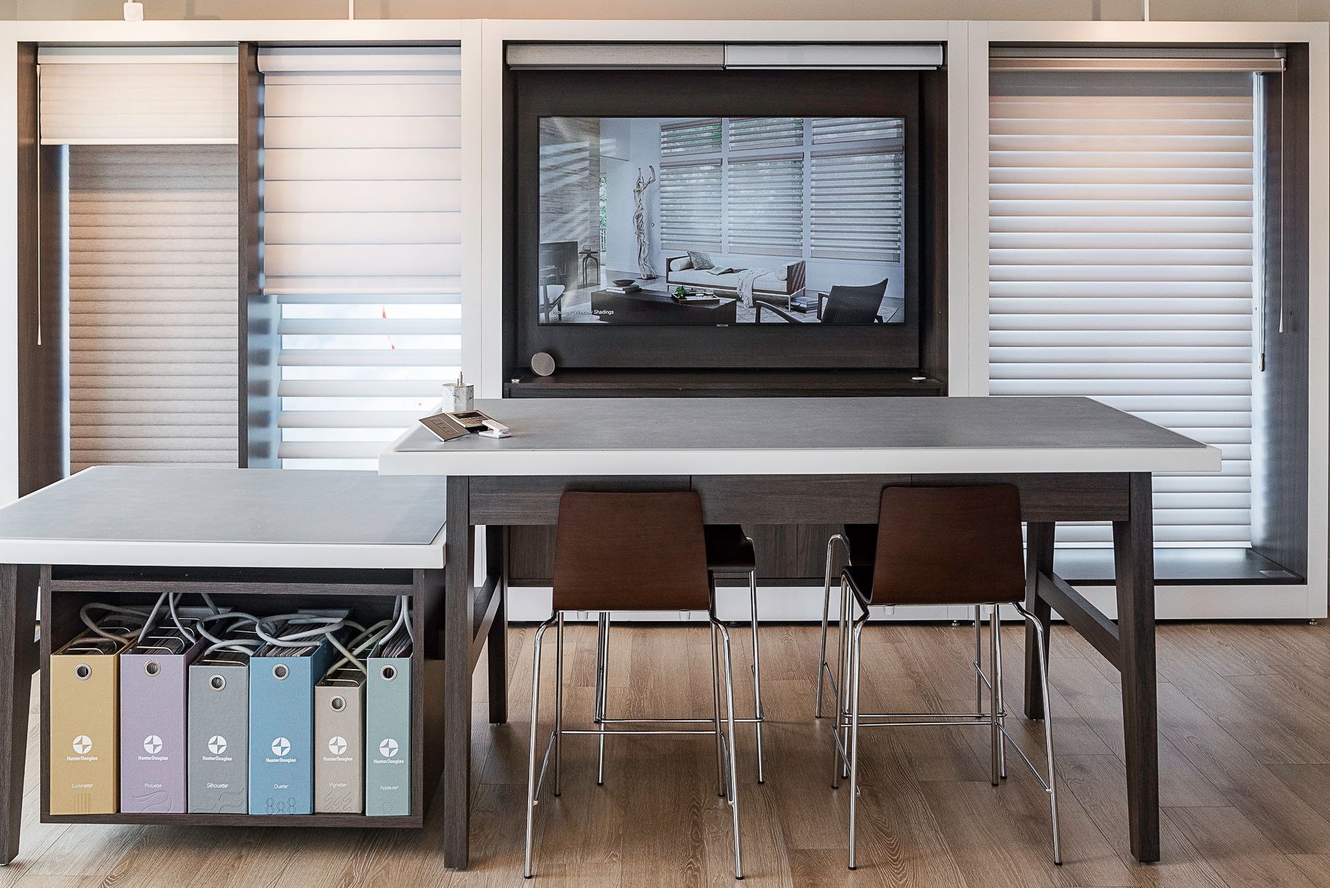 Modern office with table, chairs, wall-mounted screen, and shelving unit with storage boxes