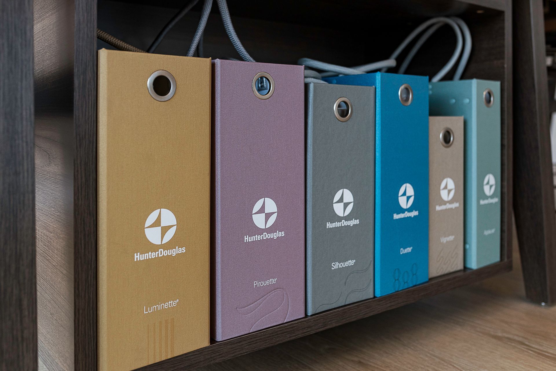 Six colorful upright file folders on a shelf, each with a circular logo and white text.